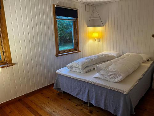a bed in a room with two pillows on it at Delightful vacation home - boat - seaview - garden in Grimstad
