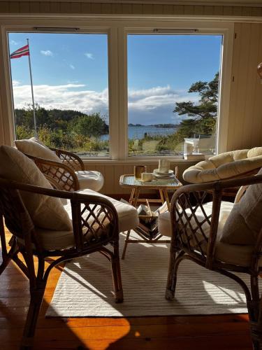 a room with chairs and a table and windows at Delightful vacation home - boat - seaview - garden in Grimstad