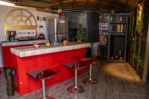 a kitchen with a red counter and red stools at EL DOMO jardín en Coyoacán in Mexico City