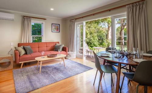 a living room with a red couch and a table at Black Cottage - Beautiful Central Cottage for Two in Rotorua