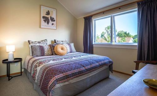 a bedroom with a bed and a large window at Black Cottage - Beautiful Central Cottage for Two in Rotorua