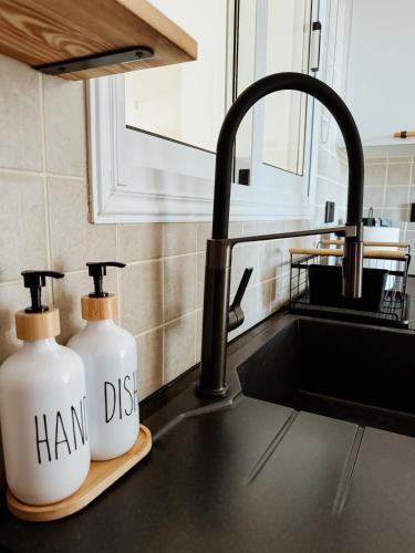 a kitchen sink with two bottles of handds on a cutting board at Nissi Si Lux Boho Apartment on Nissi beach in Ayia Napa