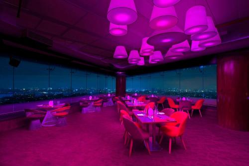 a restaurant with pink lights and tables and chairs at Sheraton Grand Bangalore Hotel at Brigade Gateway in Bengaluru