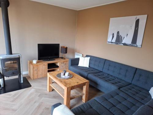 a living room with a blue couch and a tv at Holiday Home in Grou near Frisian Lakes in Grou