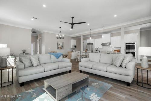 a living room with two white couches and a kitchen at Beach Retreat in Gulfport