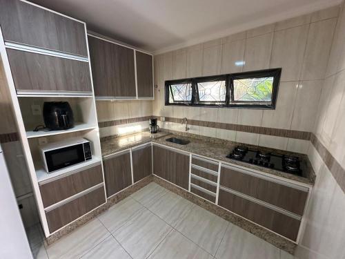 a small kitchen with a stove and a microwave at Casa Aeroporto Premium Conforto e Conveniência para Sua Estadia in Campo Grande