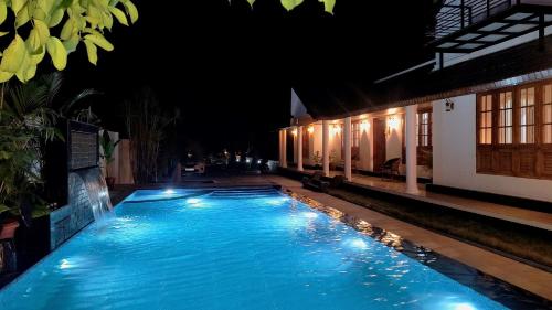a swimming pool at night with lights on it at Salisbury Manor Heritage Inn in Marayoor