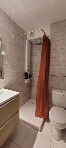 La salle de bains est pourvue de toilettes et d'une douche avec un rideau de douche orange. dans l'établissement Le Val Fleuri, à Sète