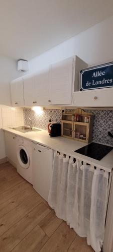 une cuisine avec des armoires blanches et une machine à laver dans l'établissement Le Studio Ombragé, à Sète