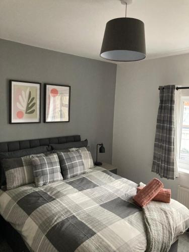 a bedroom with a bed with a plaid blanket at White Sands, NEWLY renovated central 2 bed house near Cleethorpes beach and all amenities in Cleethorpes