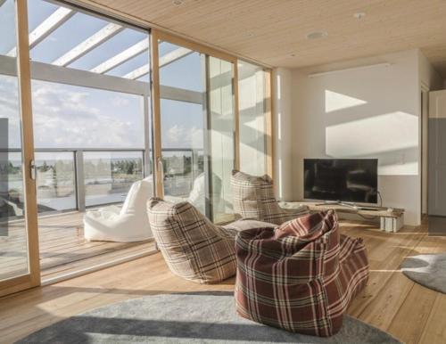 a living room with couches and a tv and glass walls at Luxury Privat Villa Merellä in Kalajoki