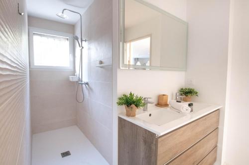 een witte badkamer met een wastafel en een spiegel bij La Villa Nature Canopée du Lac in Seignosse