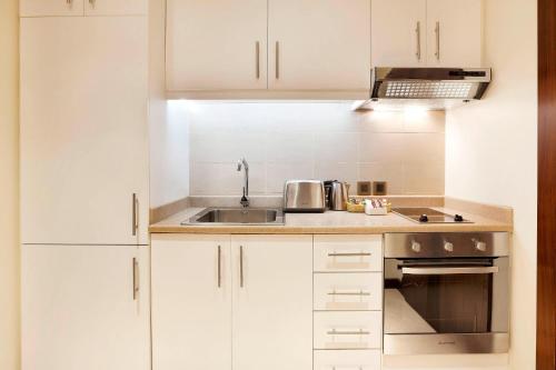 a kitchen with white cabinets and a sink at Residence Inn by Marriott Jazan in Jazan