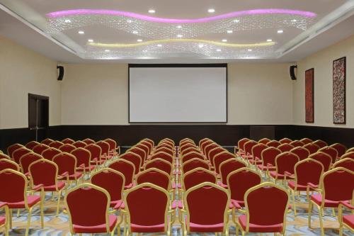 a conference room with red chairs and a screen at Residence Inn by Marriott Jazan in Jazan