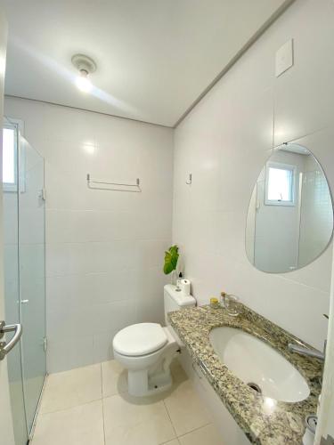 a bathroom with a toilet and a sink and a mirror at Quarto Aconchegante no Pantanal in Florianópolis