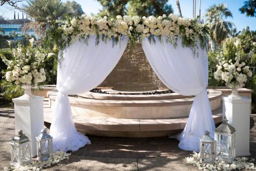 a wedding altar with white flowers and candles at Warner Center Marriott Woodland Hills in Woodland Hills