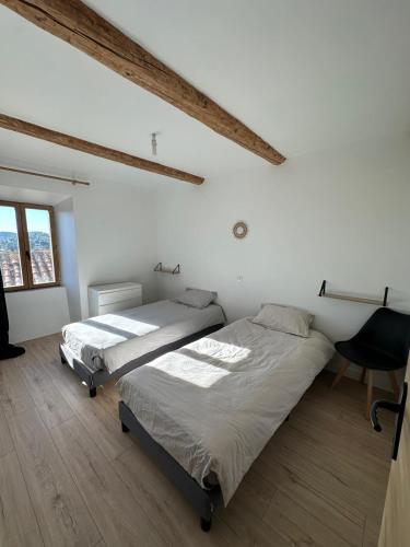 two beds in a room with white walls and wooden floors at La maison de Consuelo in Roquebrun