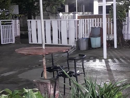 a table and two chairs in front of a white fence at Homestay larangga in Bima