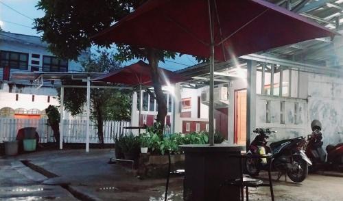 a house with an umbrella and a motorcycle in front of it at Homestay larangga in Bima
