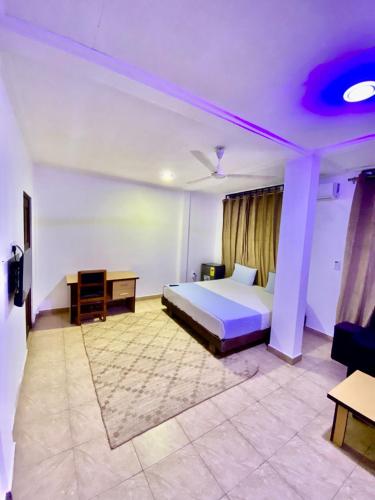 a hotel room with a bed and a desk and a bed at Eden Lodge in Cape Coast
