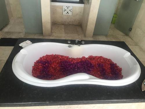 a bath tub filled with red flowers in a bathroom at One BedRoom Villa with Private Pool near DPS Airport in Kuta