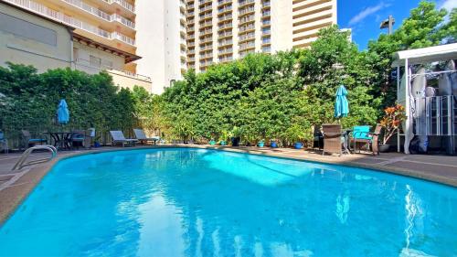 a large blue swimming pool with chairs and umbrellas at Waikiki Grand Hotel Official Site in Honolulu