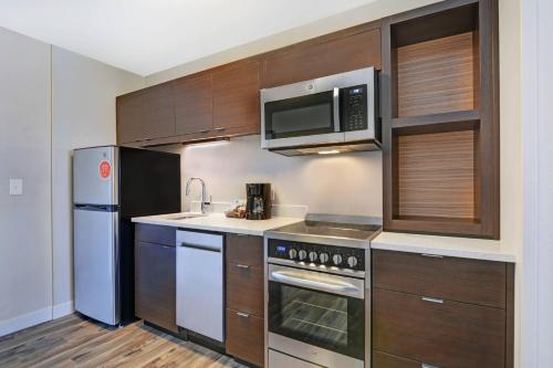 a kitchen with stainless steel appliances and wooden cabinets at TownePlace Suites by Marriott Jackson Airport/Flowood in Flowood