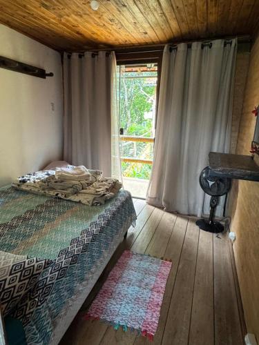 a bedroom with a bed and a window and a rug at Pousada do Sossego in Conceição da Ibitipoca