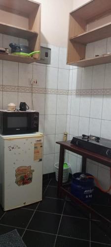 a kitchen with a microwave and a refrigerator and a table at Lablu Studio Apartment in Mombasa