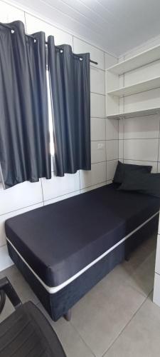 Cama grande en habitación con cortinas negras en Vila Foz HOSTEL AP3 Apartamento completo de solteiro com garagem fechada e lavanderia, Temos Uber e guia turístico para indicar, nosso apartamento é a melhor opção custo benefício de Foz do Iguaçu, en Foz do Iguaçu