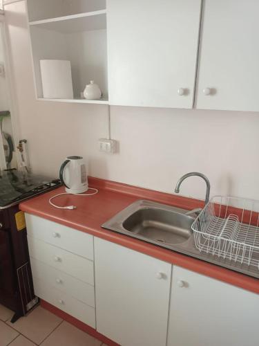 a kitchen counter with a sink and a microwave at Departamento frente a playa Bellavista in Tomé