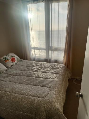 a bedroom with a bed and a window at Departamento frente a playa Bellavista in Tomé