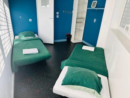 deux lits dans une chambre aux murs bleus dans l'établissement Maison de vacances aux portes de Paris, aux Lilas