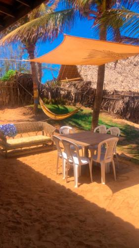 a table and chairs under a umbrella on the beach at Casa da Peroba Sol - Pé na Areia - Praia da Peroba - Icapuí in Icapuí