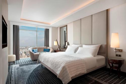a bedroom with a large white bed and a chair at Le Meridien Dhaka in Dhaka
