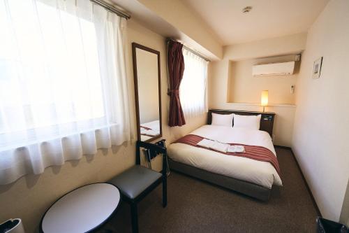 ein kleines Zimmer mit einem Bett und einem Fenster in der Unterkunft Hotel Astir Nagoya Sakae in Aoichō
