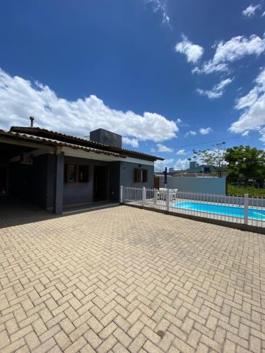 een huis met een wit hek en een betegelde oprit bij Casa com piscina capão da canoa in Capão da Canoa