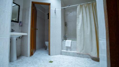 a bathroom with a shower and a toilet and a sink at Hotel Cima Argentum in Potosí