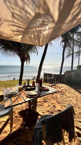 a picnic table on the beach with a view of the ocean at Casa da Peroba Sol - Pé na Areia - Praia da Peroba - Icapuí in Icapuí