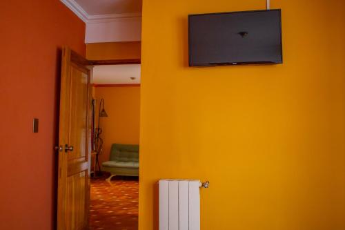 a room with a yellow wall with a flat screen tv at Hotel Cima Argentum in Potosí