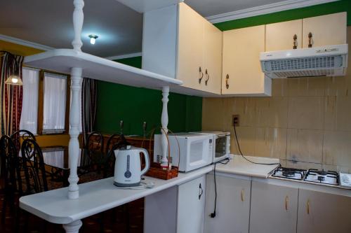 a kitchen with white cabinets and a white microwave at Hotel Cima Argentum in Potosí