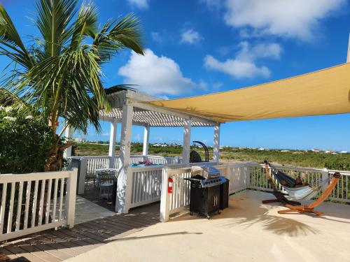 a deck with a gazebo and a palm tree at Long Bay View Villa in Leeward