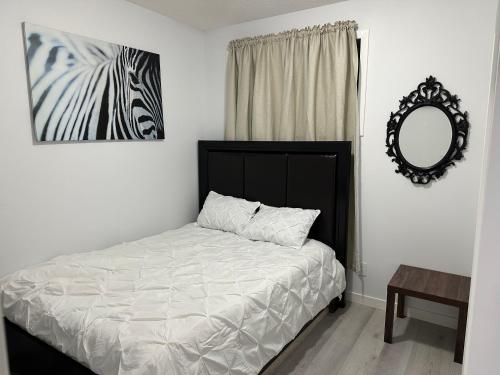 a bedroom with a bed with a mirror and a zebra picture at Muaysh Cozy Family suite - Londonderry Mall in Edmonton