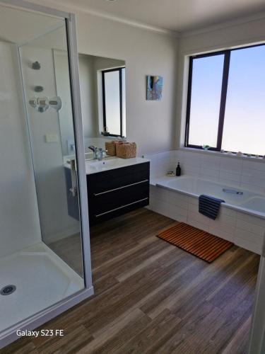 Un baño con bañera, lavabo y ducha. en Glen Wallace Lodge, en Waipu
