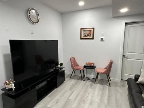 a living room with a flat screen tv and two chairs at Muaysh Cozy Family suite - Londonderry Mall in Edmonton