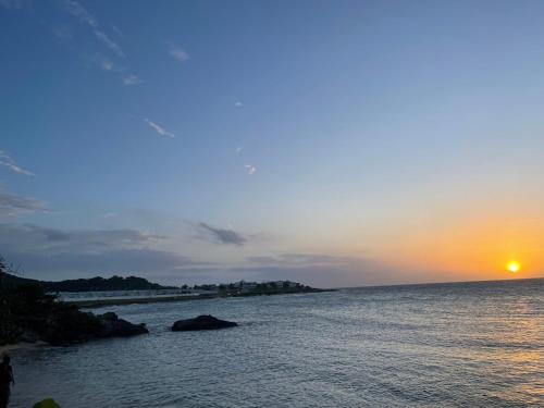 a sunset over a body of water with the sun setting at Seashell Villas in Lucea