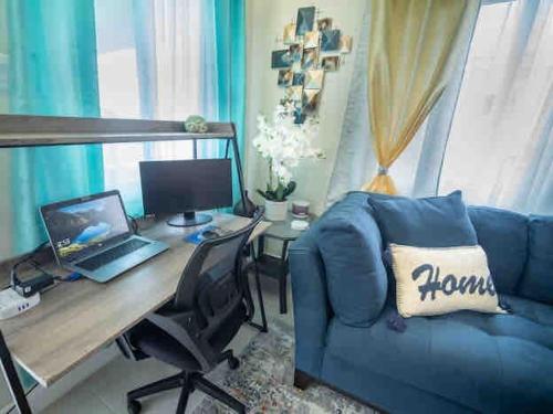 a living room with a blue couch and a desk with a laptop at Seashell Villas in Lucea