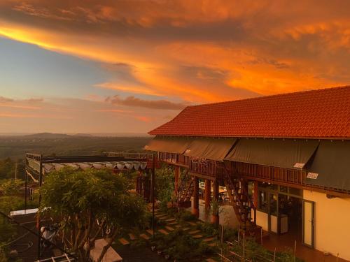 a building with a sunset in the background at Homestay Lưng Đồi in Buôn Dhă Prŏng