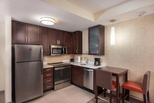 a kitchen with wooden cabinets and a stainless steel refrigerator at Residence Inn By Marriott Greenville in Greenville