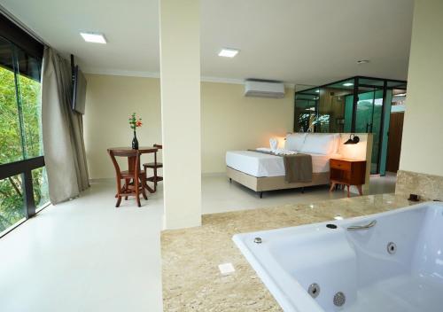 a bathroom with a tub and a bedroom with a bed at Pousada e Restaurante Mangue Seco Angra in Angra dos Reis